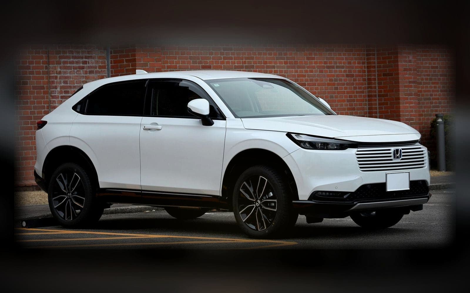 A white Honda Vezel, the compact 4x4 class, lit against a dark showroom backdrop